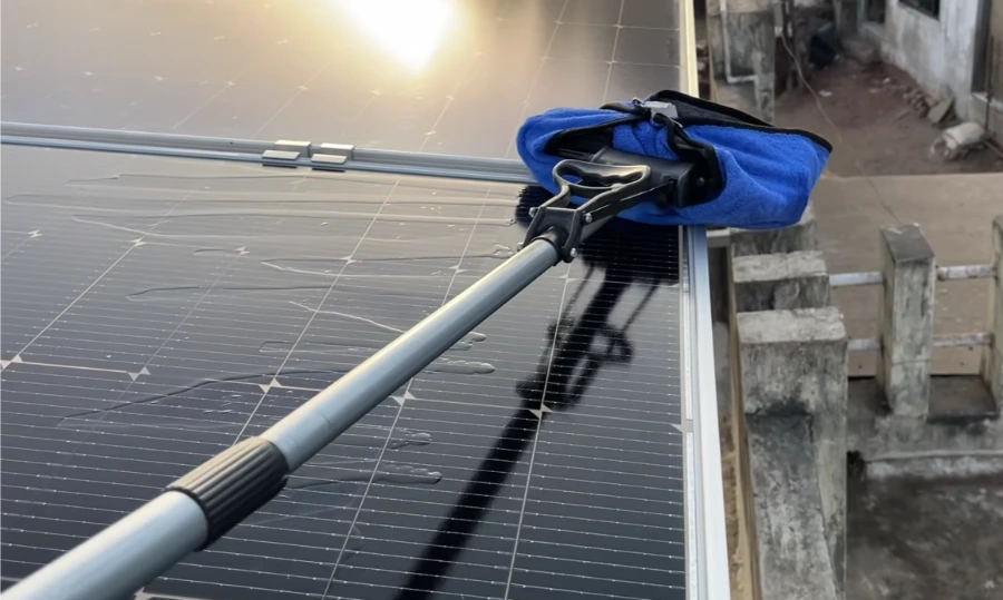 Pole-mounted microfiber pad wiping solar panels in low sun, solar panel maintenance Las Vegas