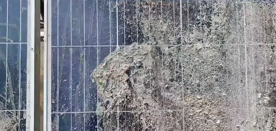 Close-up of solar panel glass caked with dried dirt and bird droppings